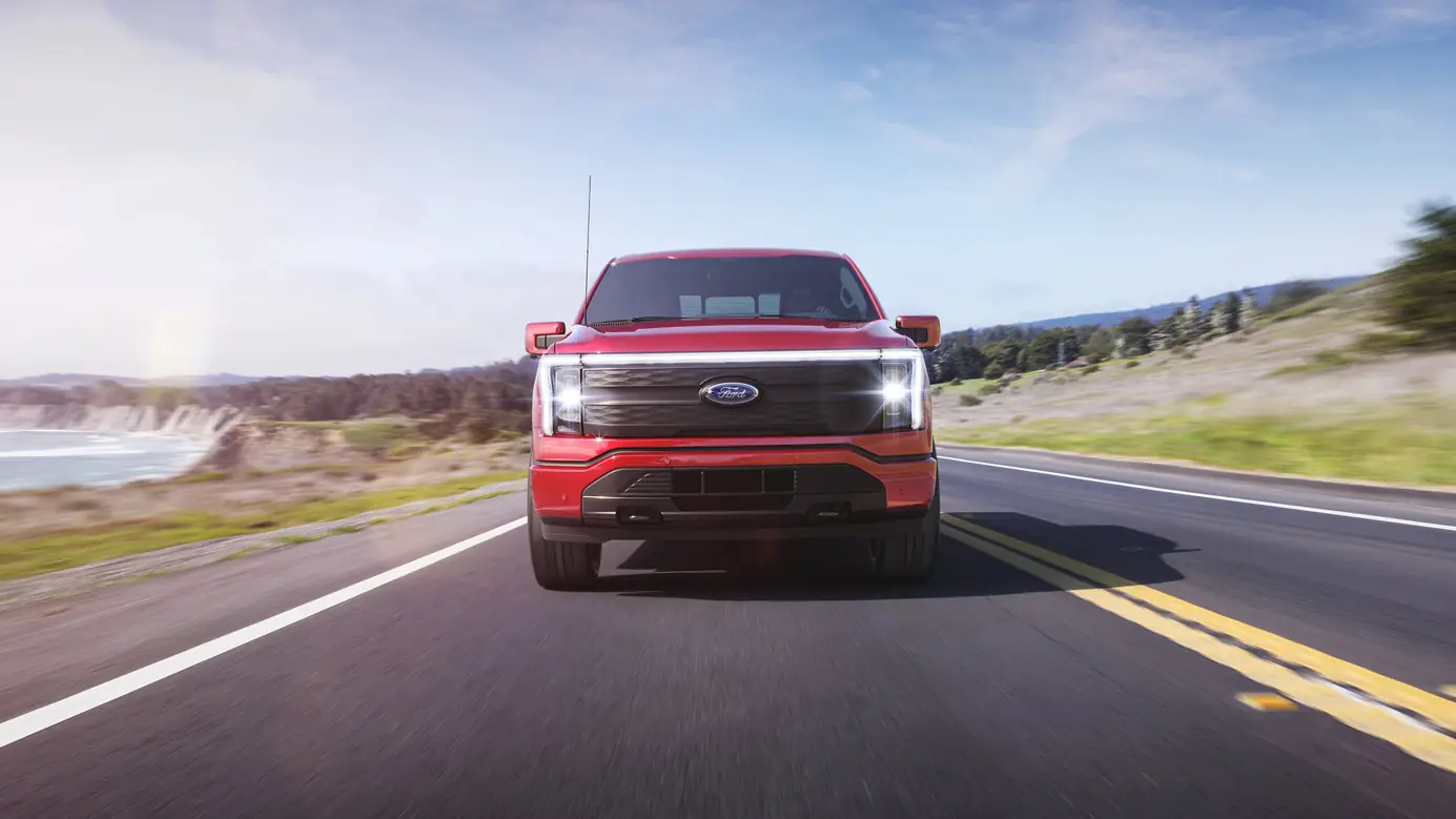 A red F-150 Lightning on a coastal highway