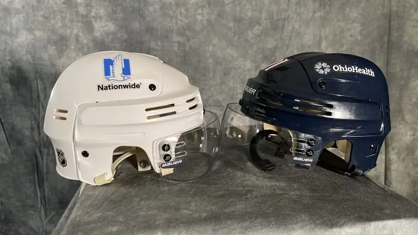A white Nationwide helmet beside a navy OhioHealth helmet