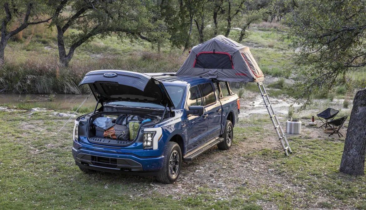 An F-150 Lightning at a campsite with its front trunk open