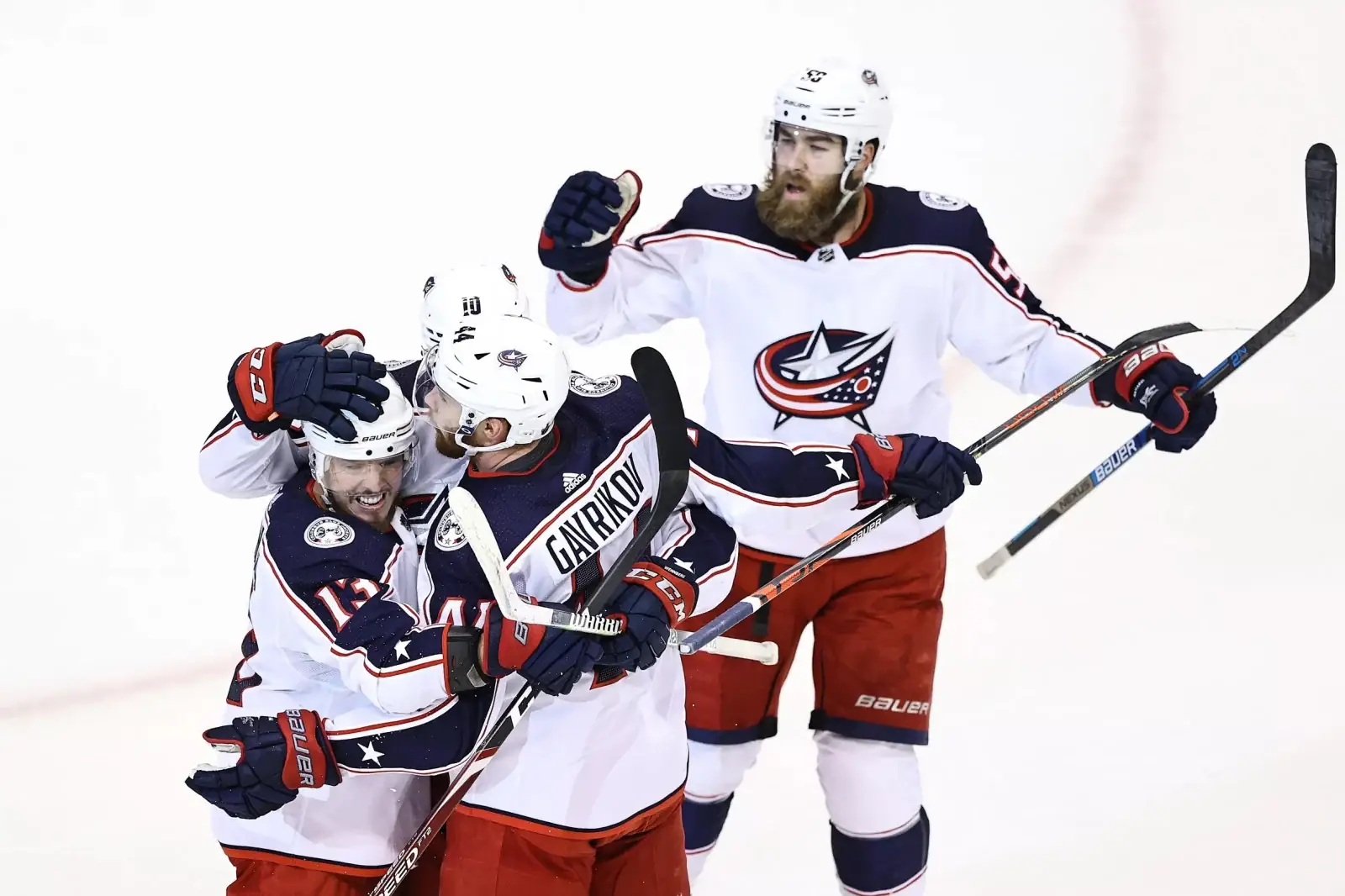 Four hockey players in Columbus Blue Jackets uniforms celebrate on the ice, with one player’s name, "GAVRIKOV," visible on…