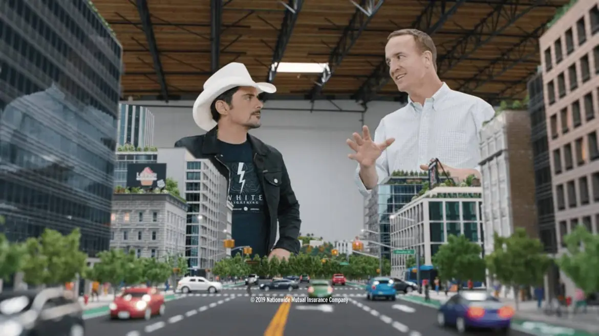 Peyton Manning and Brad Paisley talking among model skyscrapers