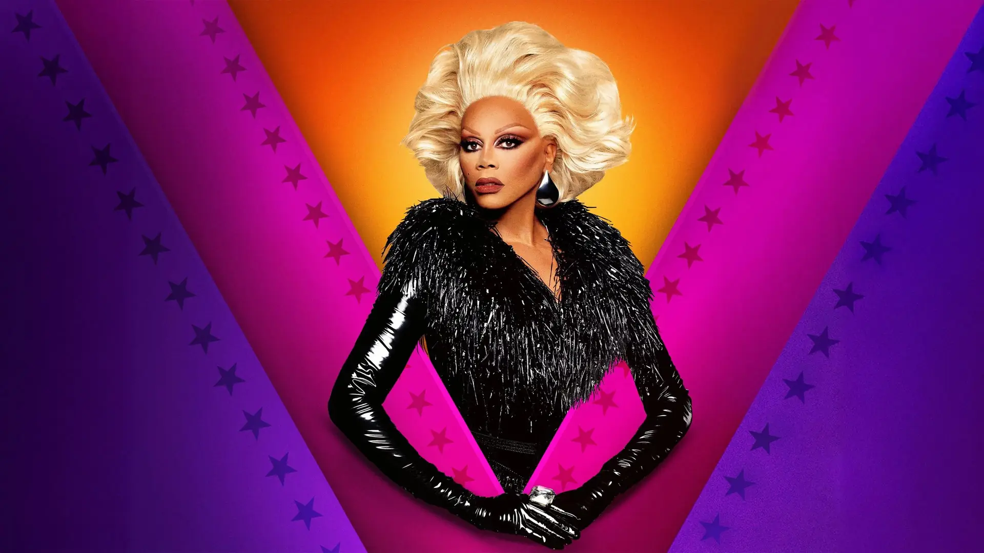 RuPaul poses in a black fringed outfit and blonde wig against a colorful background with purple stripes and stars.